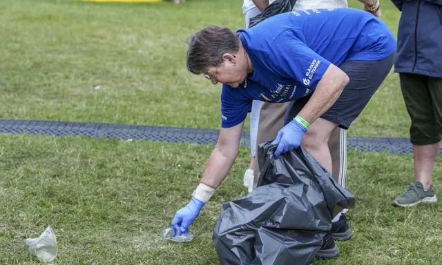 Frivillig samler affald op på græsset