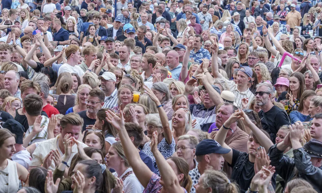 Publikum foran scenen med hænderne i vejret